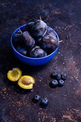 Ripe juicy plums and blueberries in a bowl on a table. Summer fruits.