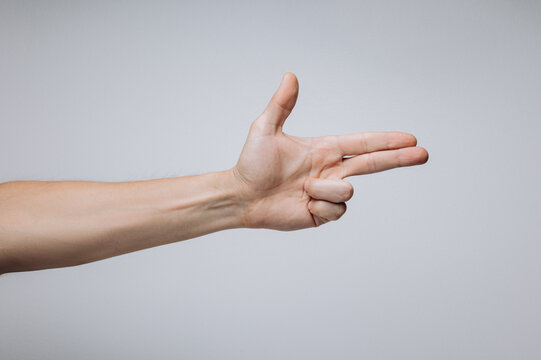 Man's hand showing gun gesture isolated over light background.