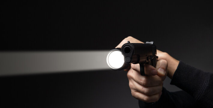 Professional security guard or policeman with flashlight and gun in dark room