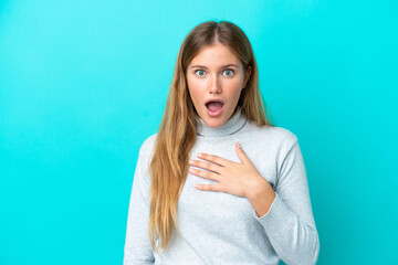Young blonde woman isolated on blue background surprised and shocked while looking right