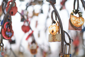 close up old rusty locks heart shaped on wire rope. Love lock on the bridge. tradition of hanging a barn lock on the wedding day