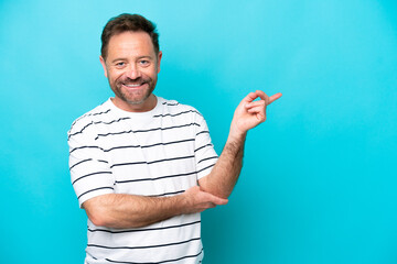 Middle age caucasian man isolated on blue background pointing finger to the side