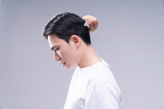 Image of young Asian man hair care on background