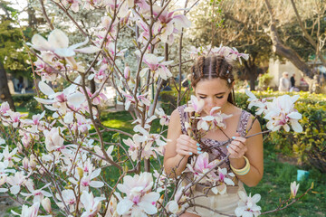 Magnolia flowers, a girl smells a blooming magnolia in the park in the sun, enjoys her vacation.