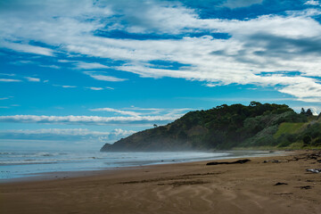 Breakers rolling over vast sand beach. Thick mist over ocean beach on a stormy day. Makorori beach, Gisborne, North Island, New Zealand