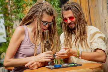 Hippie style couple smoking medical marijuana using a bong