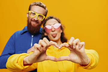 Man and woman couple smiling cheerfully and crooked with glasses, on yellow background, symbols...