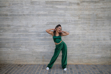 Latin woman, young and beautiful dancing modern dance on a background of gray cement in the street makes different expressions and postures. Concept dance, hip hop, dance, art, action, youth art.