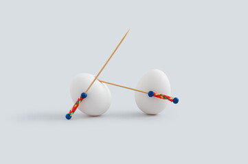 Creative Easter concept with two  white eggs and toothpicks used as spear or sword.