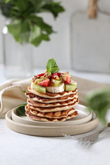 Stack of pancakes with strawberries, nuts and fruits.