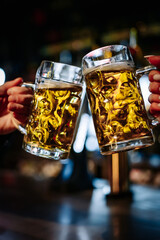 man and woman hands clinking with glasses of beer