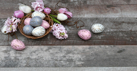 Nest mt pastellfarbenen Ostereiern dekoriert mit Blumen auf einem schäbigen Holzhintergrund mit...