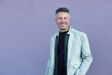 Middle-aged man posing over lilac wal. Handsome mature man. Outdoor male portrait.