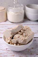 Fresh compressed yeast on white wooden table