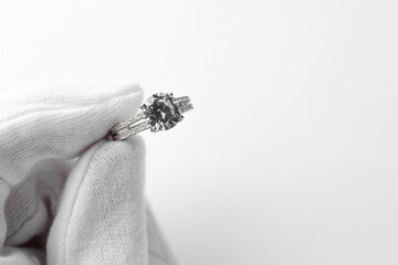 Jeweler holding diamond ring on white background, closeup. Space for text