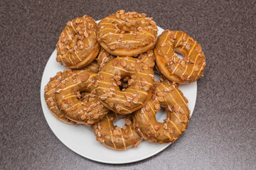 Many sweet and tasty round doughnuts, ring donuts covered with sugar. Chocolate-frosted doughnut. Symbol of sweeties, fried dough. A lot of sweet unhealthy food. Food waste, food production.