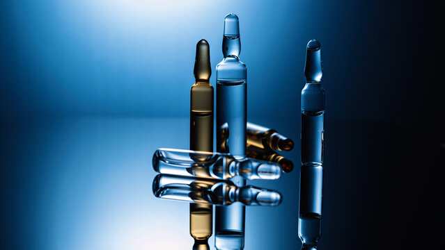 Medical drugs, ampoules with injections, vaccination, health care, close-up, dark background with blue backlight, place for text