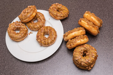 Many sweet and tasty round doughnuts, ring donuts covered with sugar. Chocolate-frosted doughnut. Symbol of sweeties, fried dough. A lot of sweet unhealthy food. Food waste, food production.