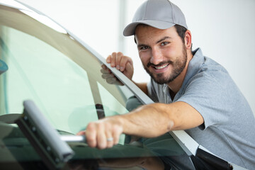 portrait of happy male worker cleaning car windshield