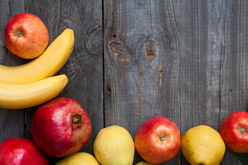 Ripe fruit on wooden background: banana, apple, pear and pomegranate