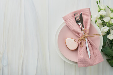 Easter brunch table setting. Spring Easter holiday concept with white, pink plate and napkin with decorative symbols holiday rabbit, eggs and bouquet of flowers on white background. Top view. Mock up.