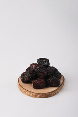 Ajwa dates on a wooden mat with white background