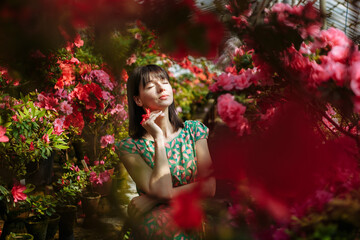Obraz na płótnie Canvas A girl in a green dress in a flower park on a sunny day
