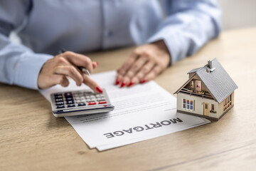 Detail of female hands using calculator to find out the interest rate on a house mortgage