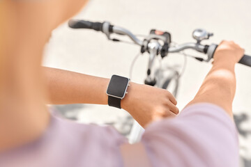 people, leisure and sport - close up of woman with smart watch riding bicycle on city street