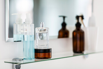 hygiene, beauty and daily routine concept - close up of lotion, perfume and moisturizer on mirror...