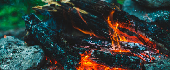 Vivid smoldered firewoods burned in fire closeup. Atmospheric background with orange flame of...