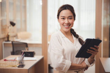 Smiling young asian working woman or businesswoman with computer laptop in office