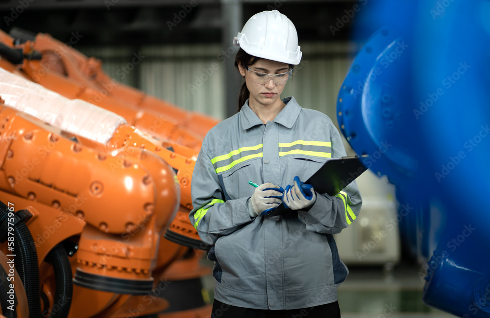 Wall mural Industrial engineer working on robot maintenance in AI futuristic electronic technology factory. Female technician checking automated robotic machine. Modern smart woman empowerment in industry 4.0.