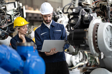 Industrial engineer working on robot maintenance in AI futuristic electronic technology factory. Female technician checking automated robotic machine. Modern smart woman empowerment in industry 4.0.