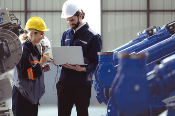 Industrial engineer working on robot maintenance in AI futuristic electronic technology factory. Technician team checking automated robotic machine. Modern smart woman empowerment in industry 4.0.