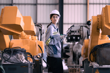 Industrial engineer working on robot maintenance in AI futuristic electronic technology factory. Female technician checking automated robotic machine. Modern smart woman empowerment in industry 4.0.