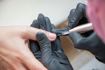 a master does a manicure to a client in a beauty salon and covers her nails