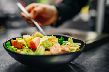 Chef cooking Caesar salad on restaurant kitchen