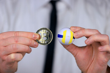 A businessman in a white shirt and black tie holding volleyball ball and bitcoin in his hands.