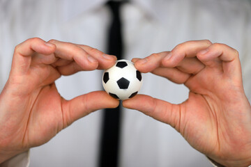 A businessman in a white shirt and black tie holding football ball in his hands.