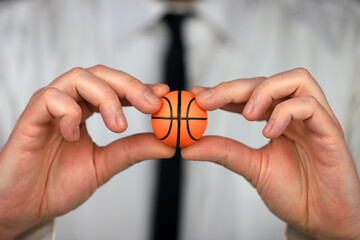 A businessman in a white shirt and black tie holding basketball ball in his hands.