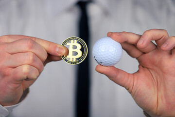 A businessman in a white shirt and black tie holding golf ball and bitcoin in his hands.