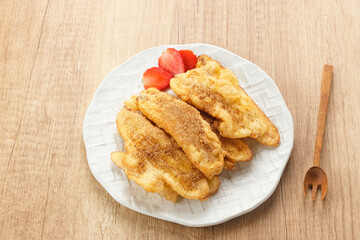 Pisang Goreng or banana fritters with a sprinkling of palm sugar served in white plate. Indonesian food
