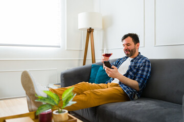 Handsome man resting and relaxing with a glass of wine at home