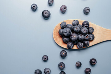 blueberries in a wooden spoon on a blue background. view from above. blueberry flat