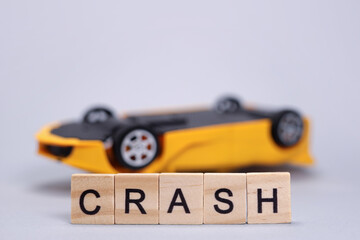 Toy upside down car and word Crash, accident concept, auto insurance