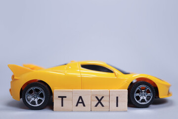 Toy car and the taxi made of wooden letters, cab passenger transportation concept