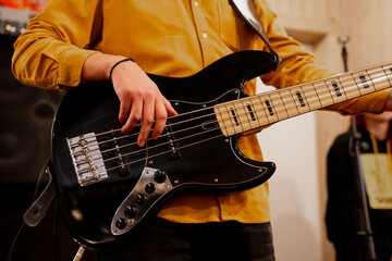 Obraz na płótnie Canvas Musician in yellow shirt playing bass guitar