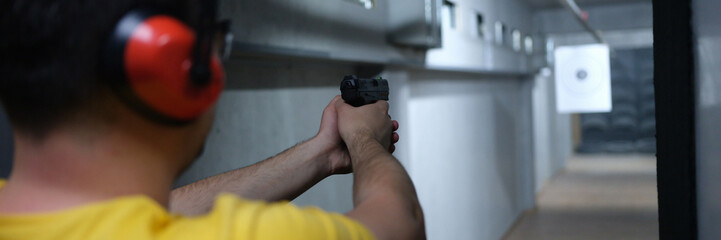 Shooter shoots from pistol in shooting range closeup