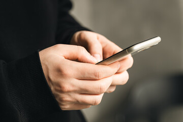 Smartphone in the hands of a man close-up on a blurred background, the concept of using technology, shopping online, communicating remotely.